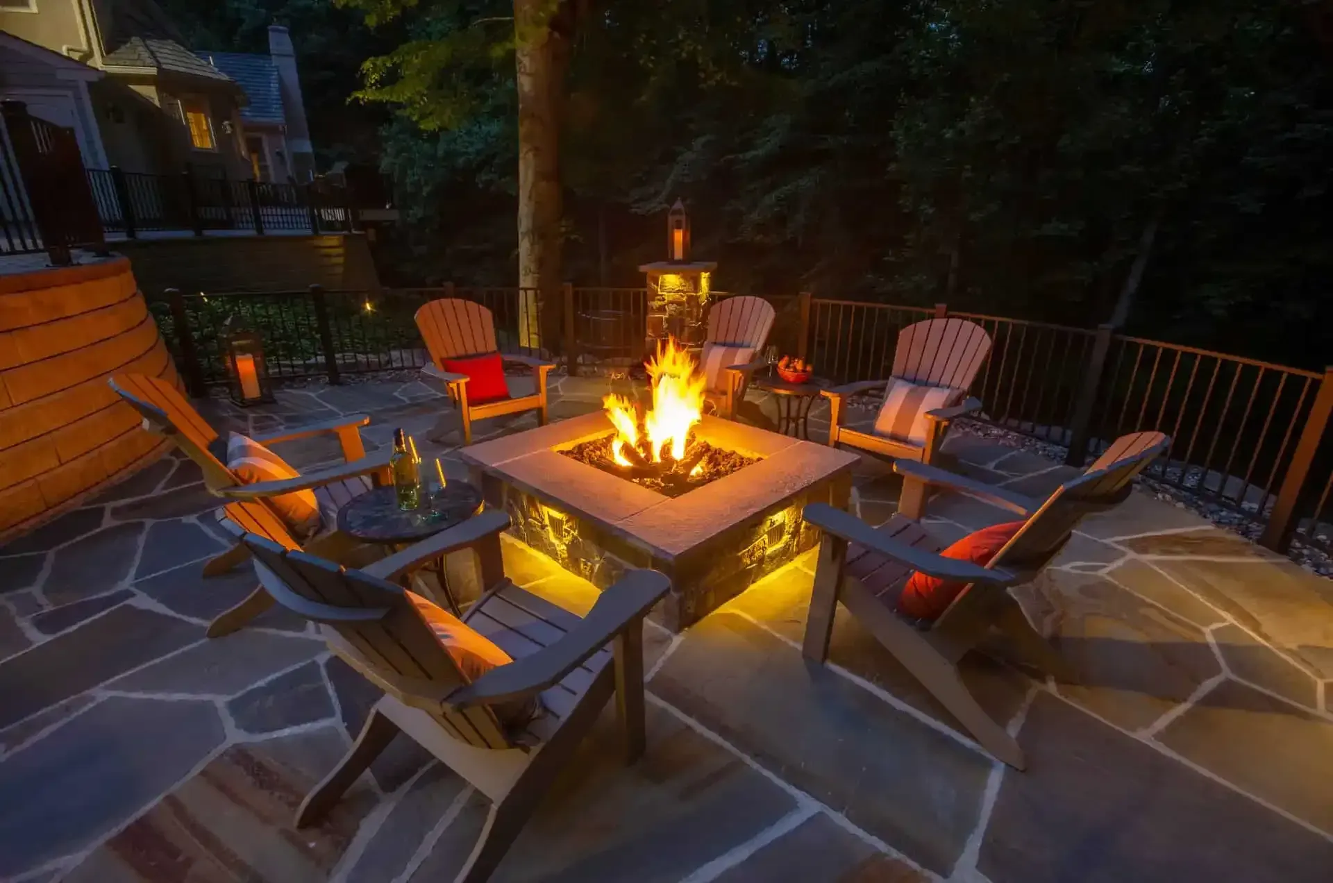Backyard patio with fire pit and Adirondack chairs glowing at dusk
