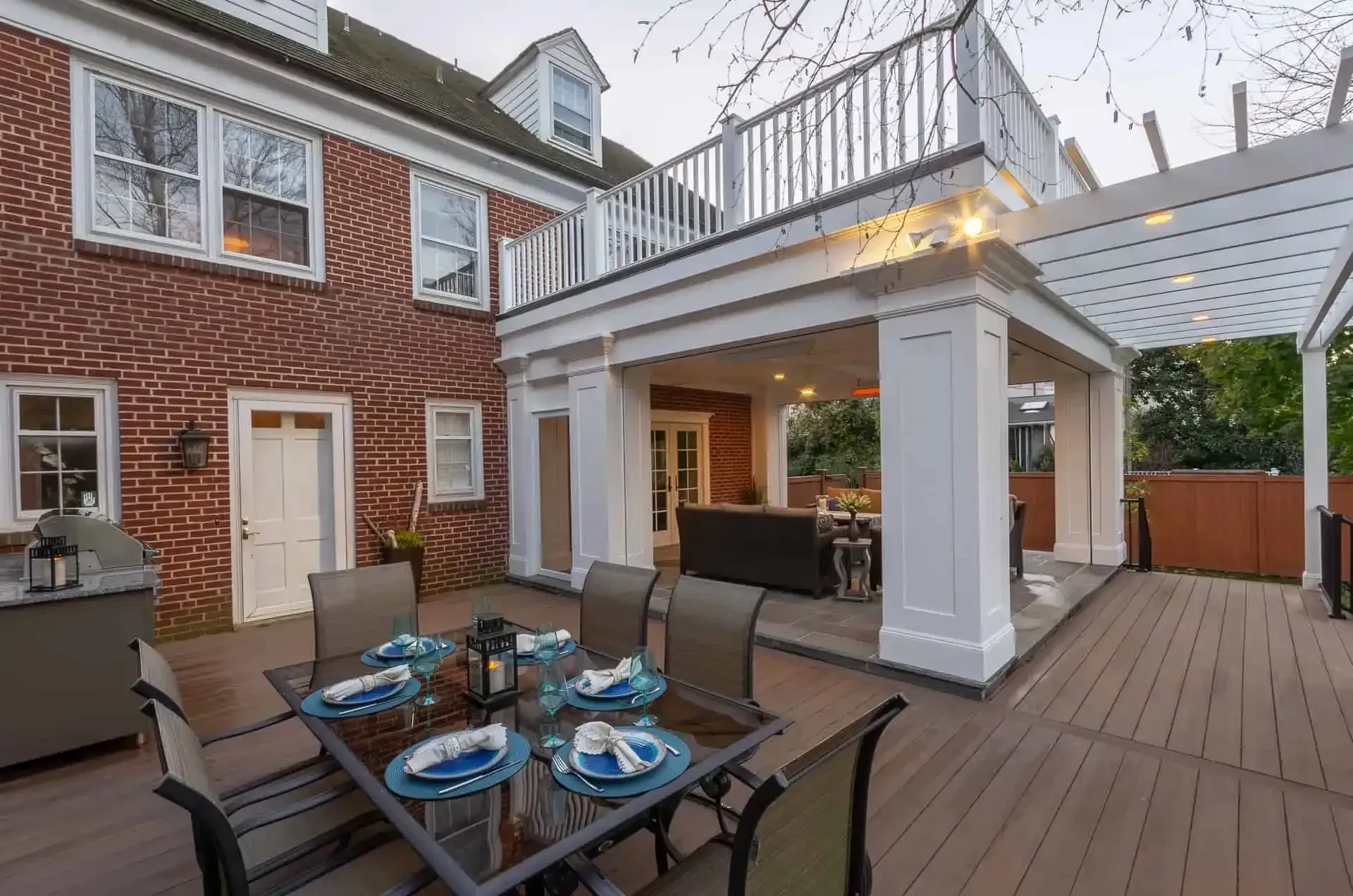 Patio deck with outdoor dining table, seating, and pergola attached to a brick townhouse