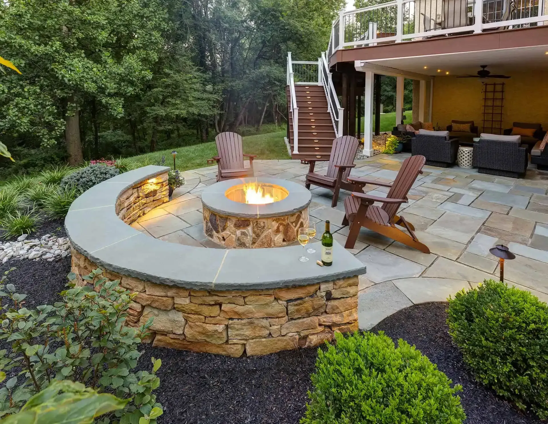 Backyard patio with circular fire pit, Adirondack chairs, and stone seating wall