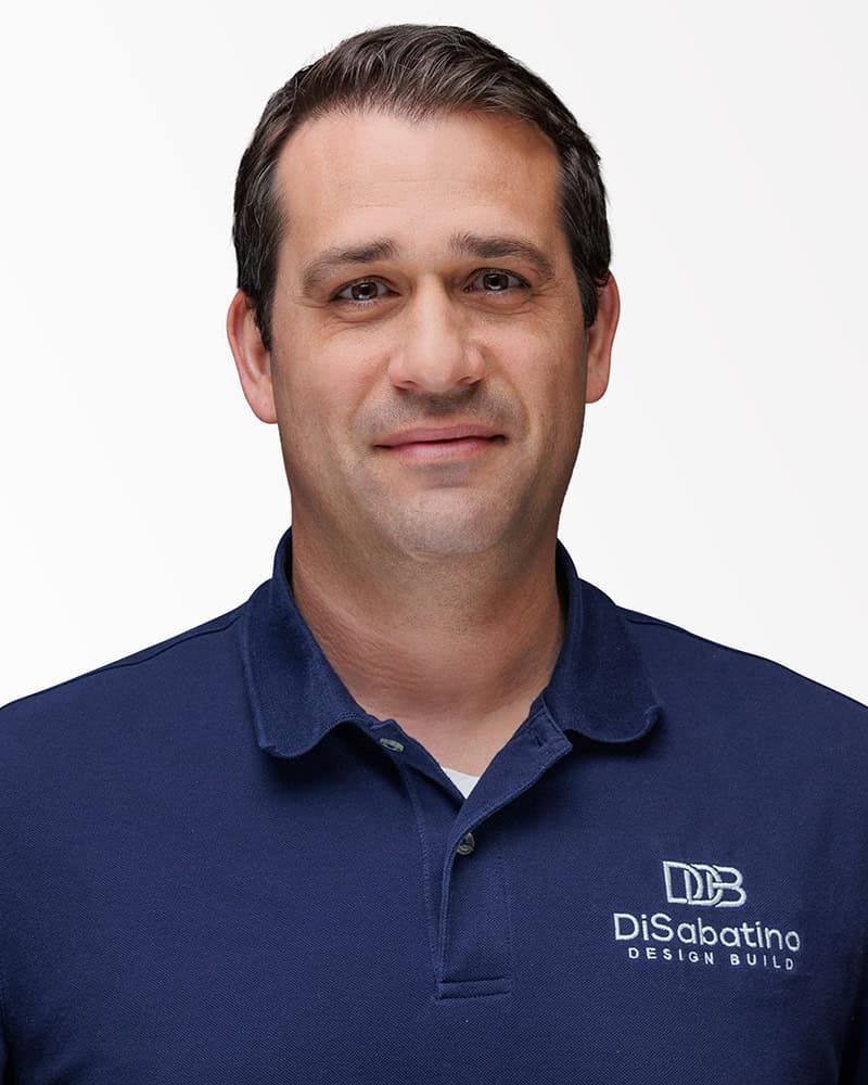 Portrait of a man in a navy polo shirt with a Disability logo on a white background