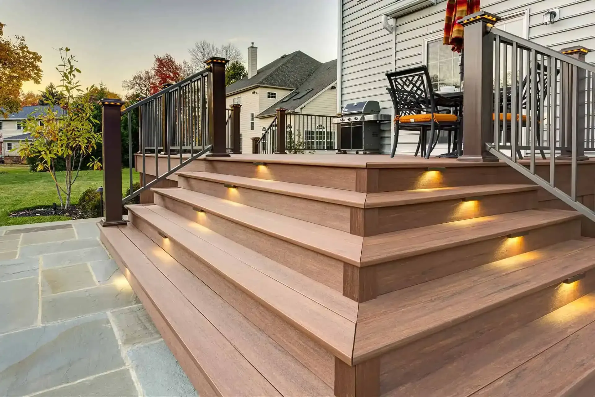 Modern wooden deck steps with recessed lights leading to a patio and outdoor seating area