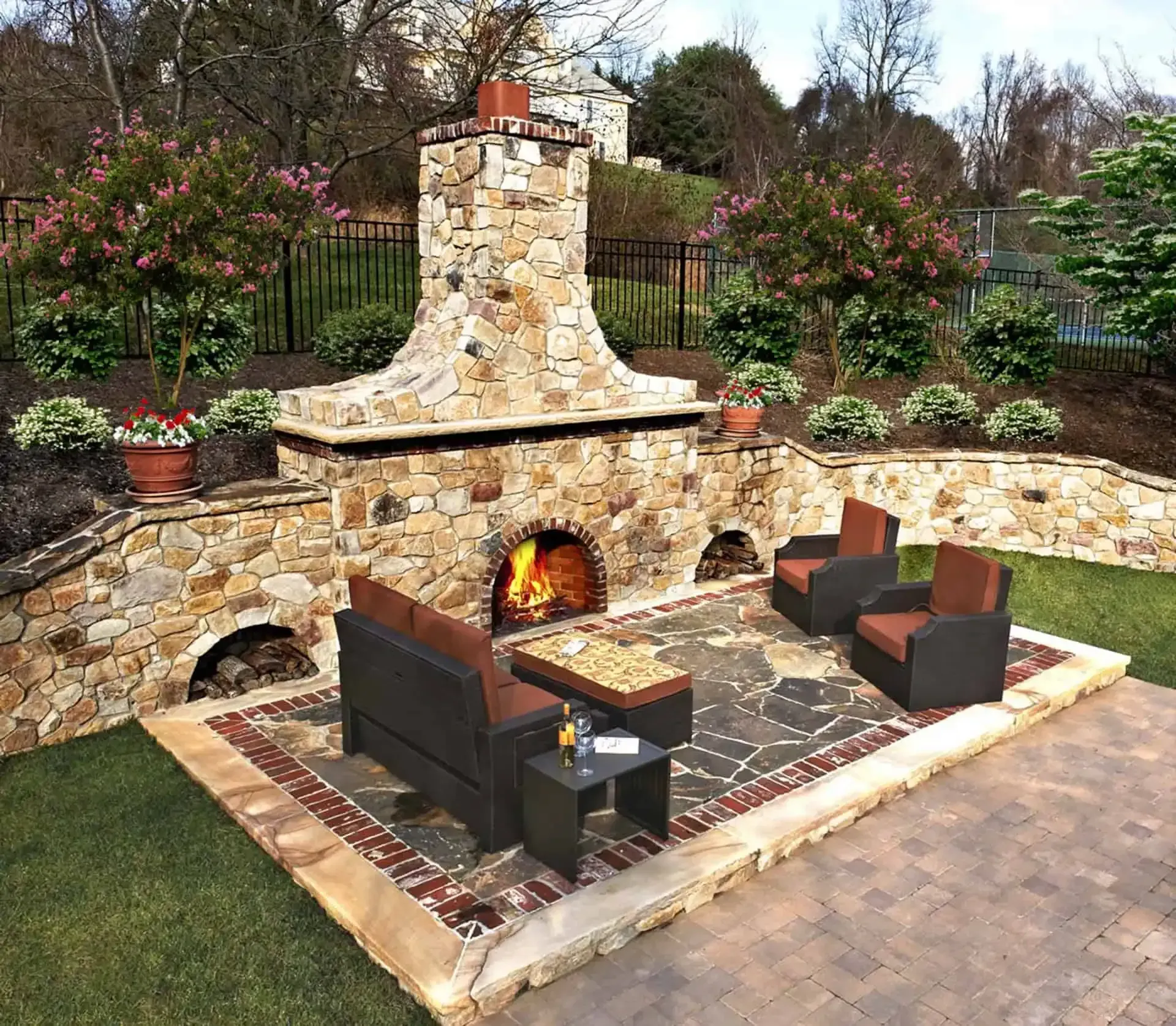 Outdoor stone fireplace with seating area and patio furniture in a backyard garden