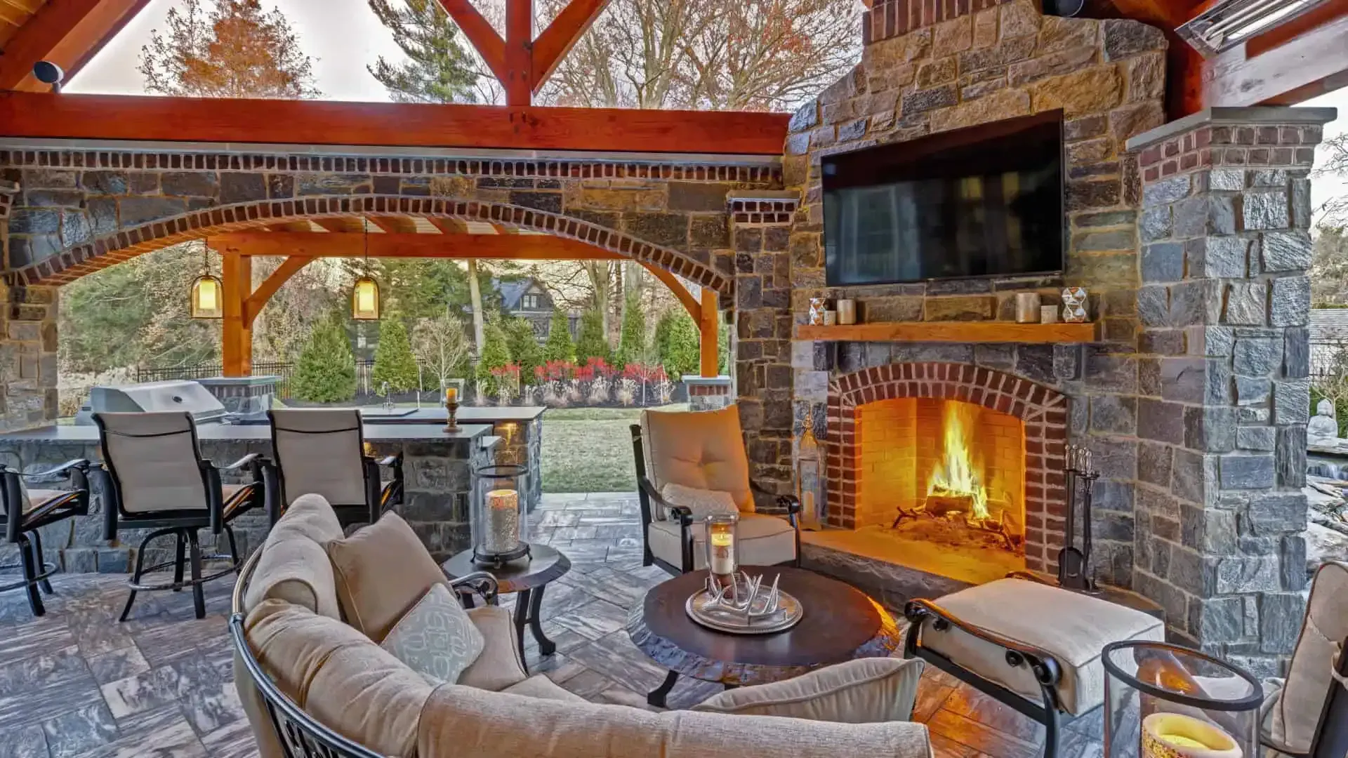 Cozy stone patio with fireplace, covered seating, and outdoor dining area at sunset