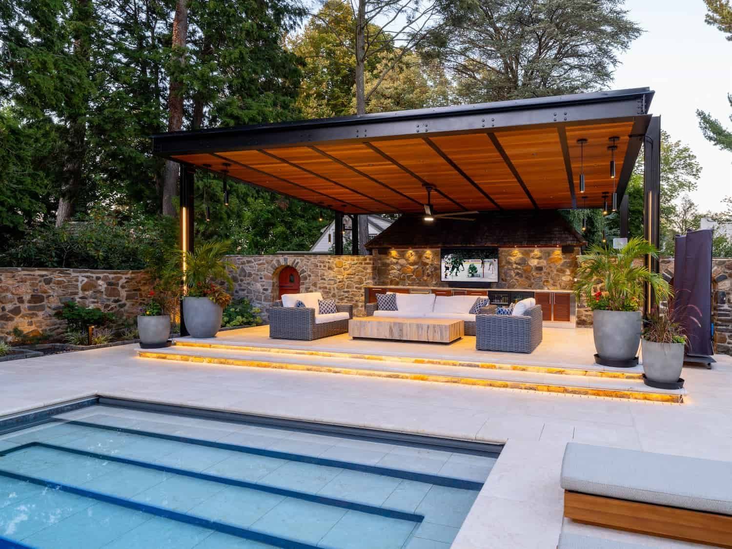 Modern outdoor patio lounge with covered seating beside a blue swimming pool
