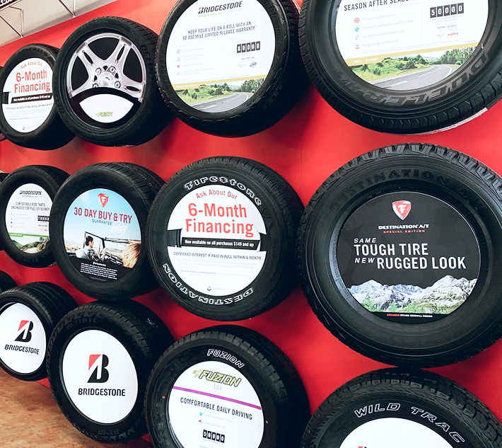 Wall of black tire displays with red background and tires | Cornerstone Tire Complete Auto Care