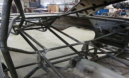 A metal frame of a car is being built in a garage.