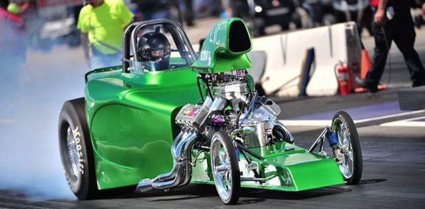 A green racing car is driving down a race track.