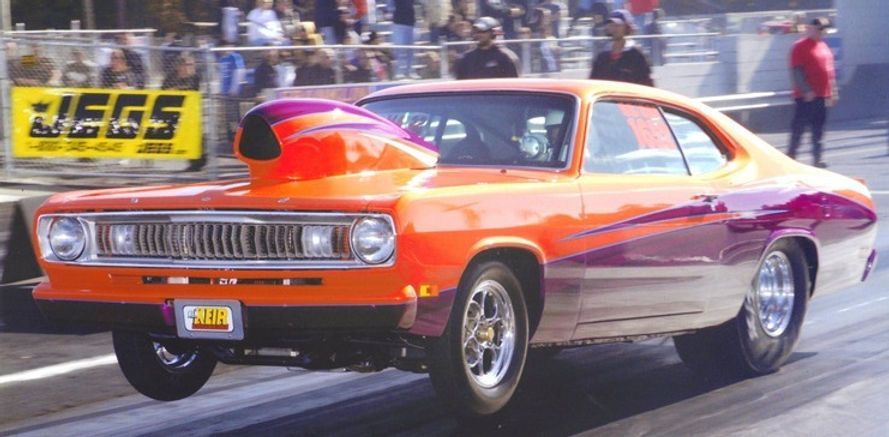 An orange and purple car is driving down a race track.