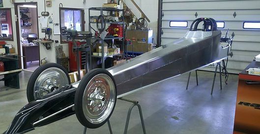 A dragster is sitting on a table in a garage.