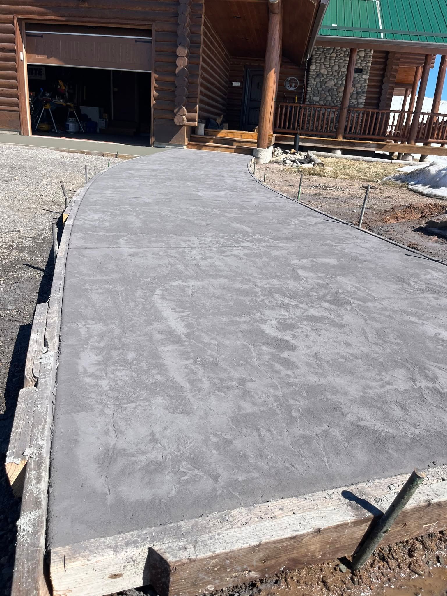Freshly poured concrete walkway leading to a wooden building under construction