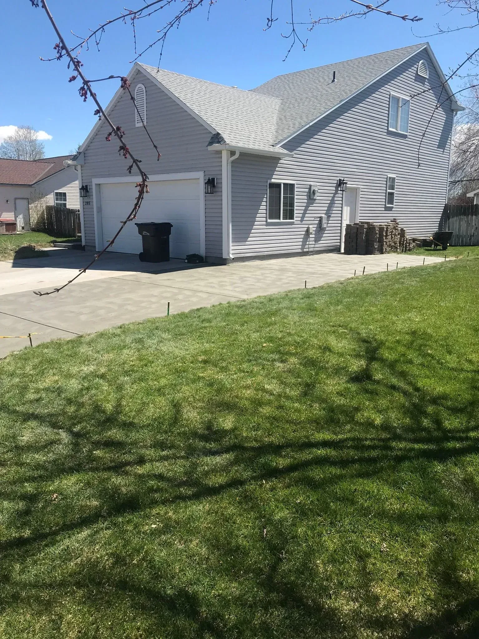 Suburban house with white siding, sloped roof, driveway, and green front lawn on a sunny day