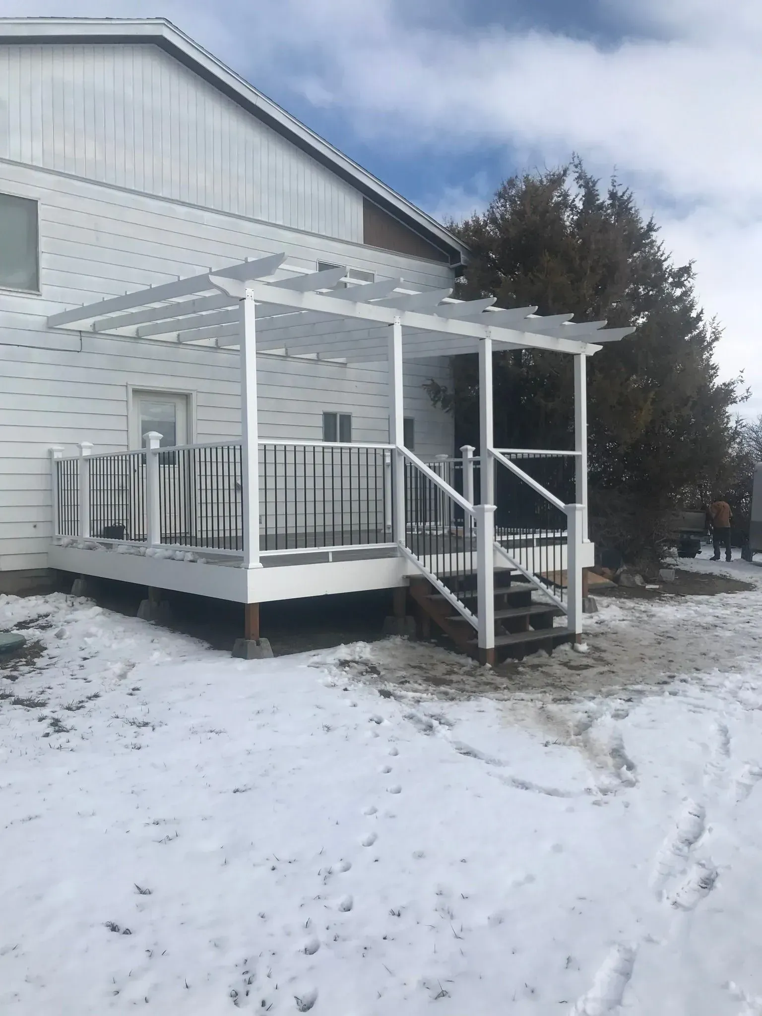 Snow-covered white house with a small porch and steps in a winter yard