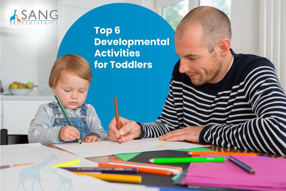 A man and a child are sitting at a table drawing with pencils.