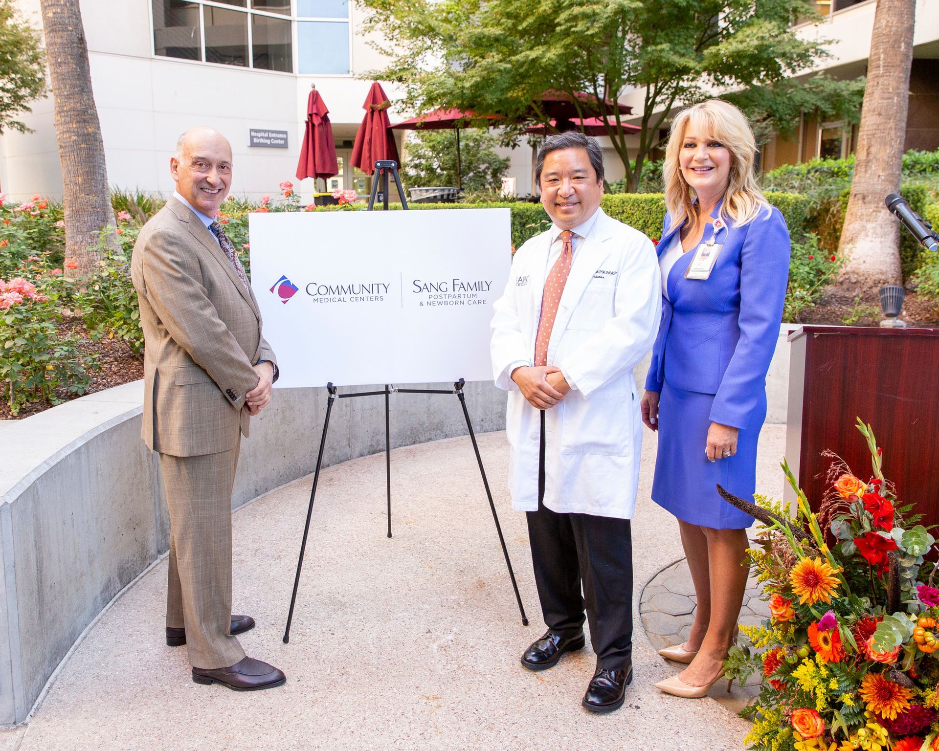 Three people standing next to each other in front of a sign