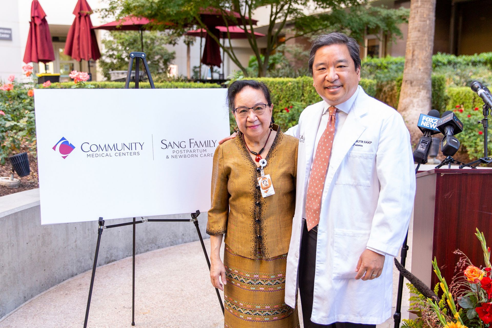 A man and a woman are standing next to each other in front of a sign.