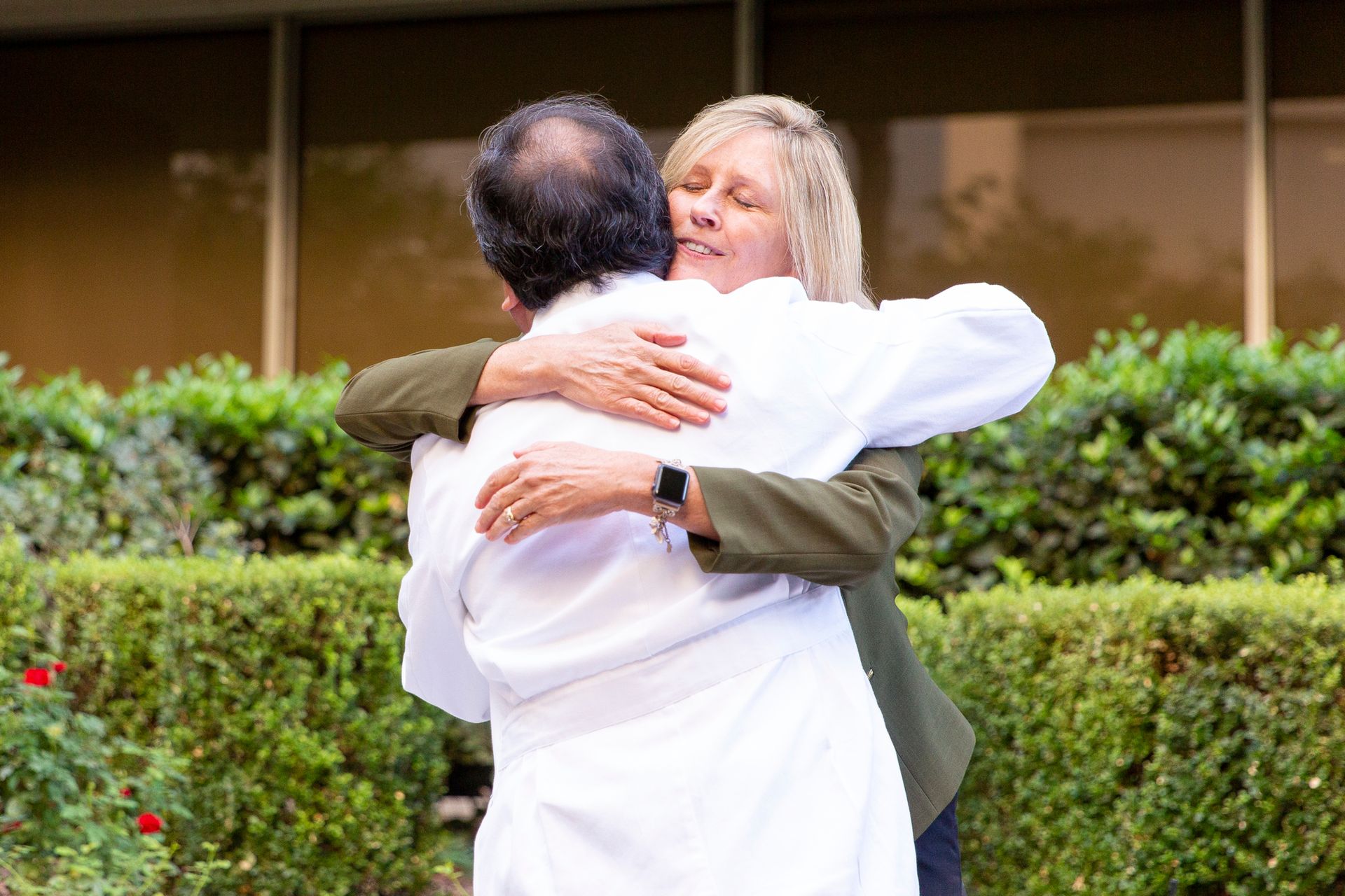 A woman in a white coat is hugging a man in a white coat.