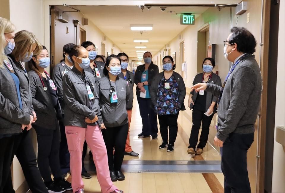 A group of nurses wearing masks are standing in a hallway.