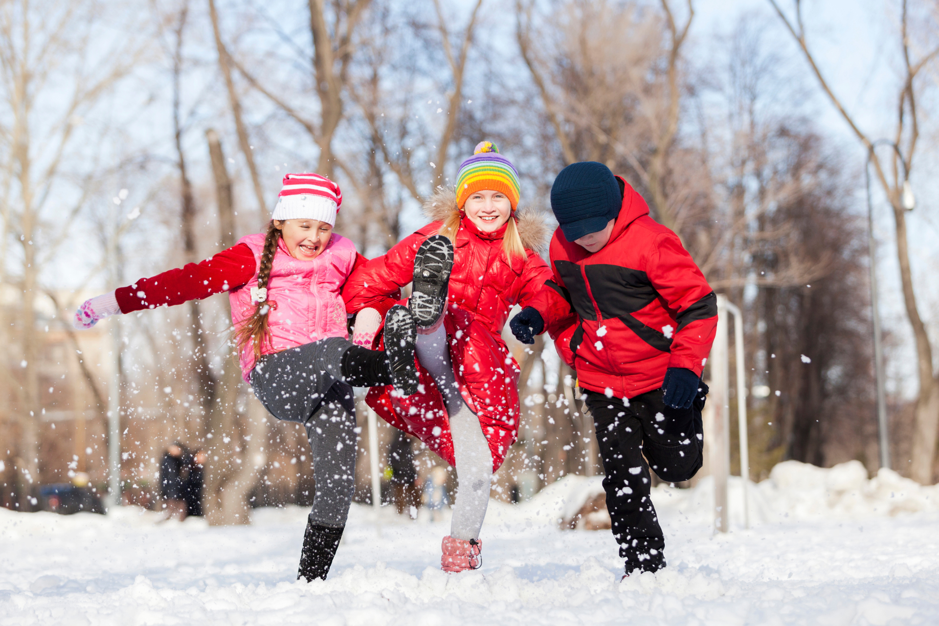 Three kids playing in the snow happily after their sports physical appointment.