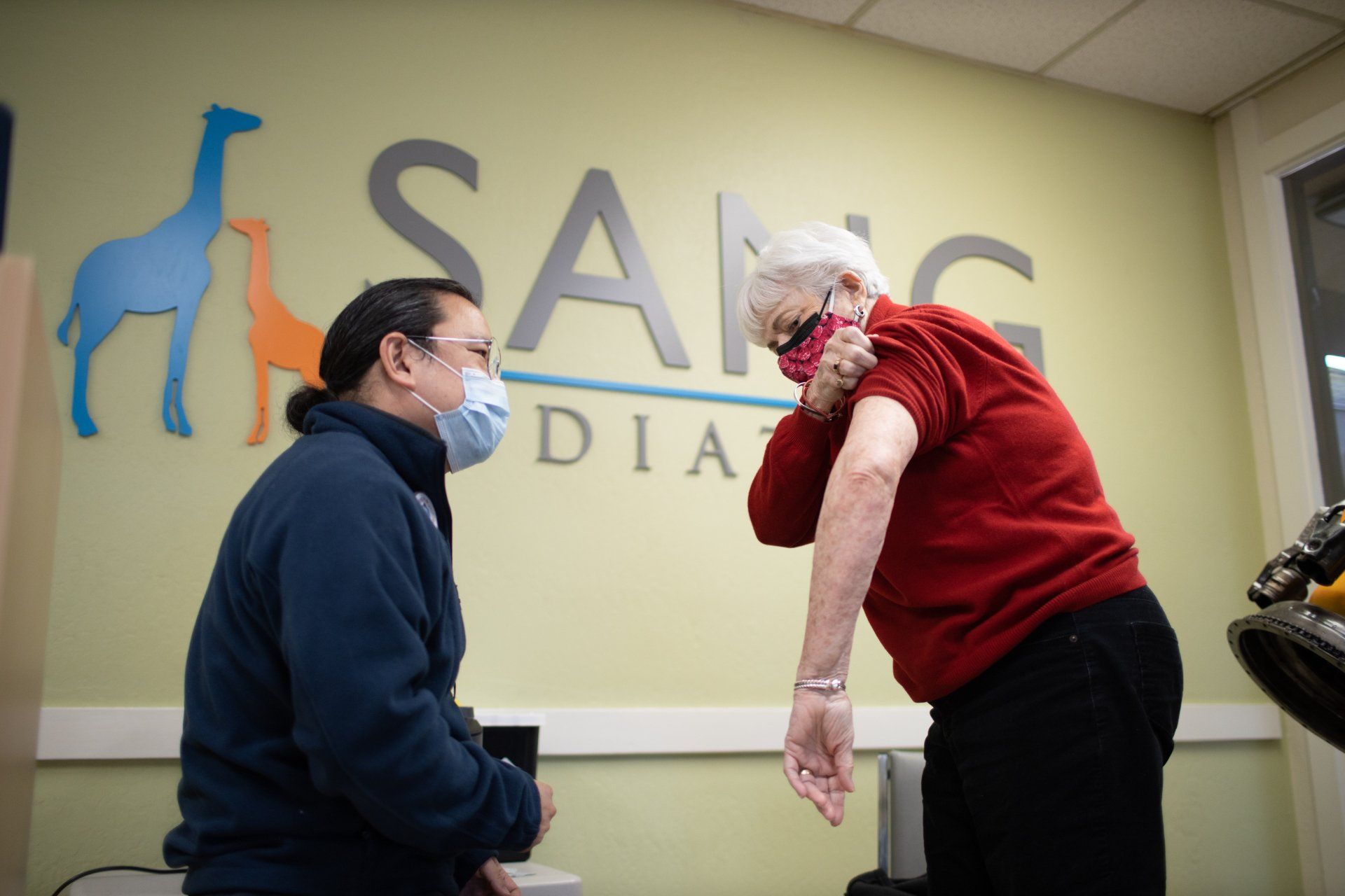 A man wearing a mask is getting a vaccine from a doctor.