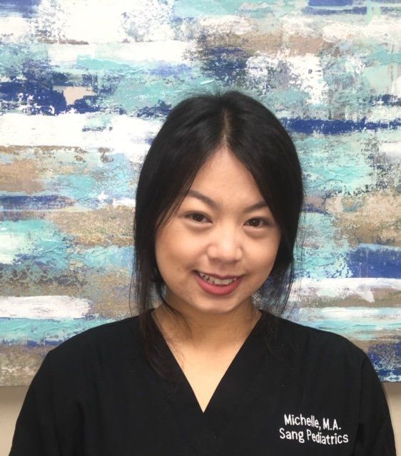 Michelle sang pediatrics is smiling in front of a painting
