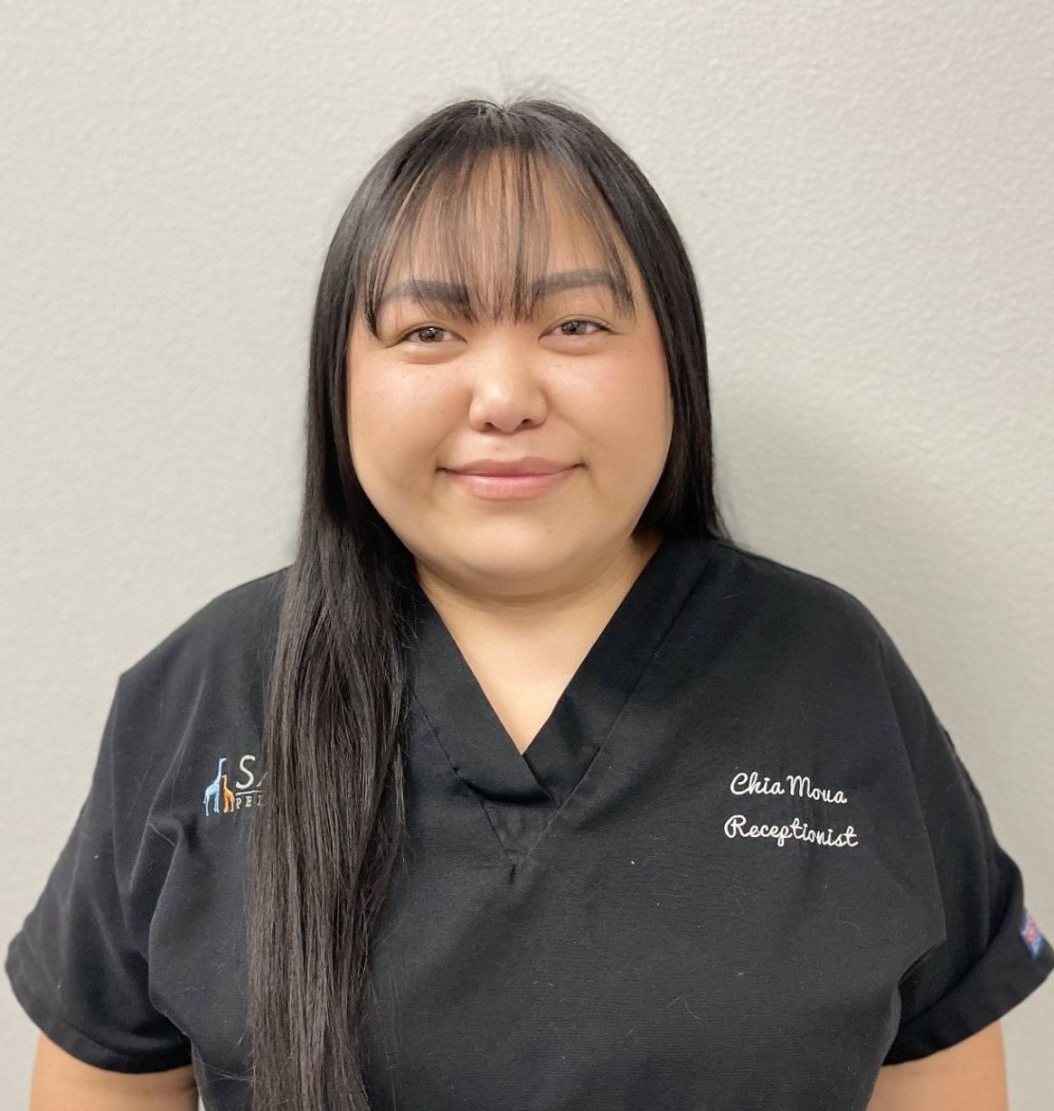 A woman wearing a black scrub top with the name chris on it