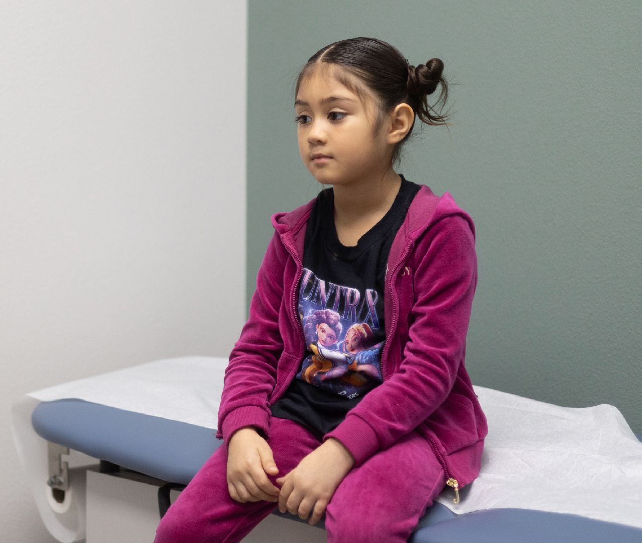 A little girl is sitting on an exam table
