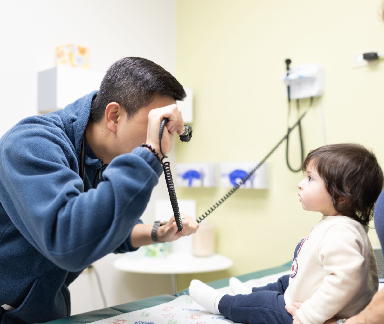 A little girl is sitting on an exam table with a doctor.