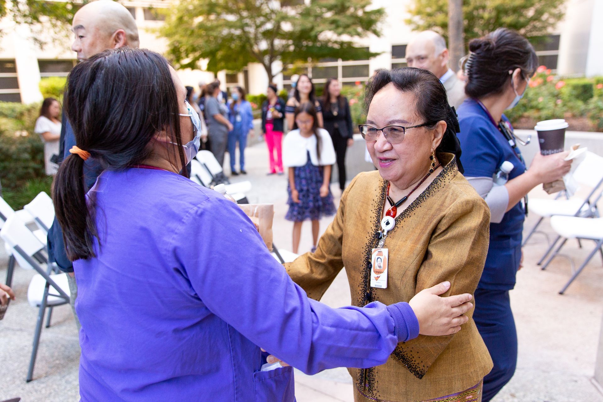 A woman in a purple shirt is hugging another woman in a brown jacket.