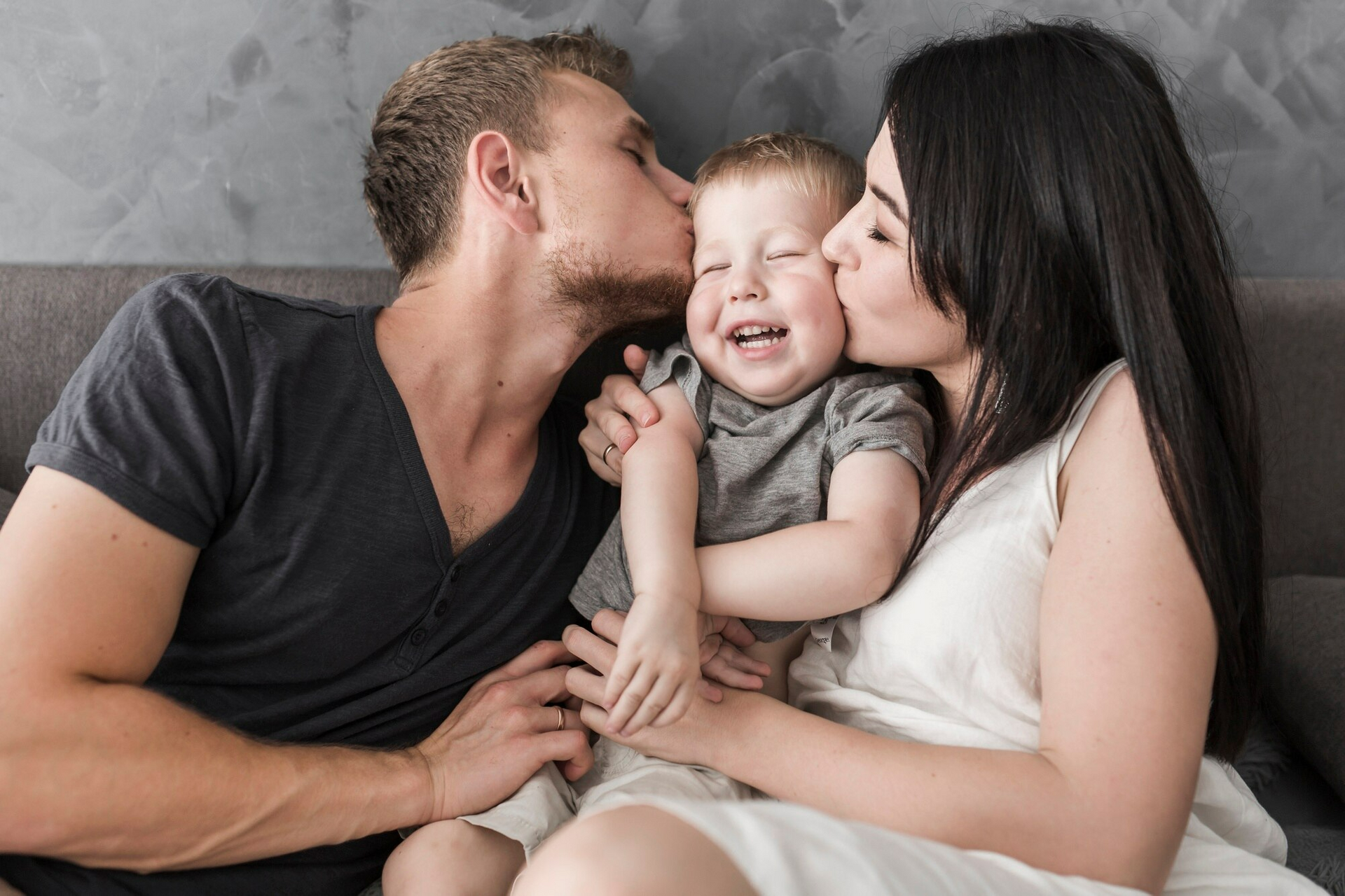 Parents kissing their child and showering him with love and care.