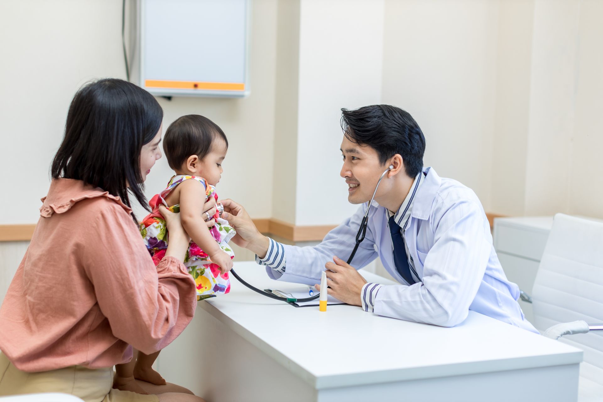 A doctor is using a stethoscope to listen to a baby 's heartbeat.