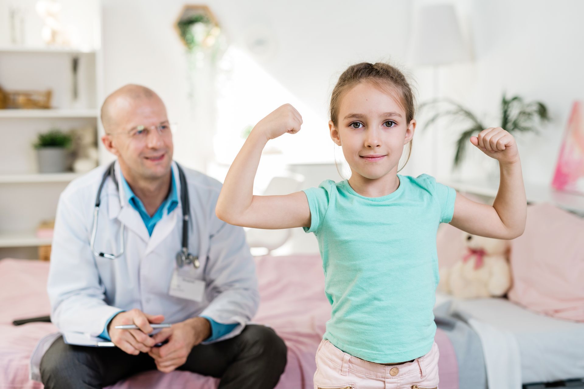 A little girl is flexing her muscles in front of a doctor.