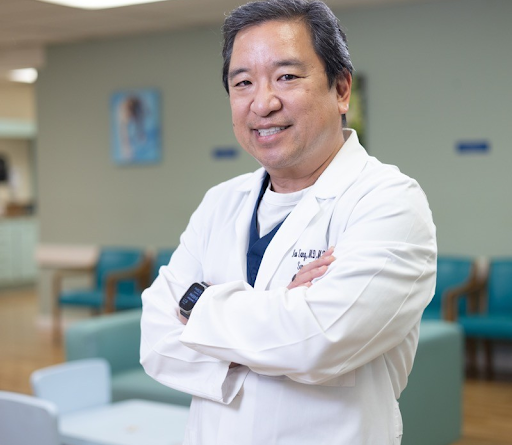 A doctor with his arms crossed is smiling for the camera