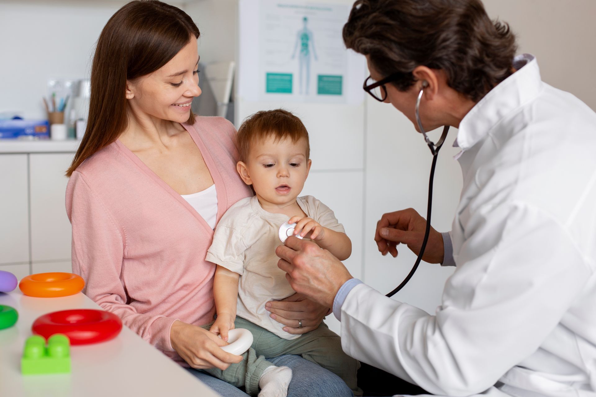 A doctor is examining a baby with a stethoscope while a woman holds the baby.