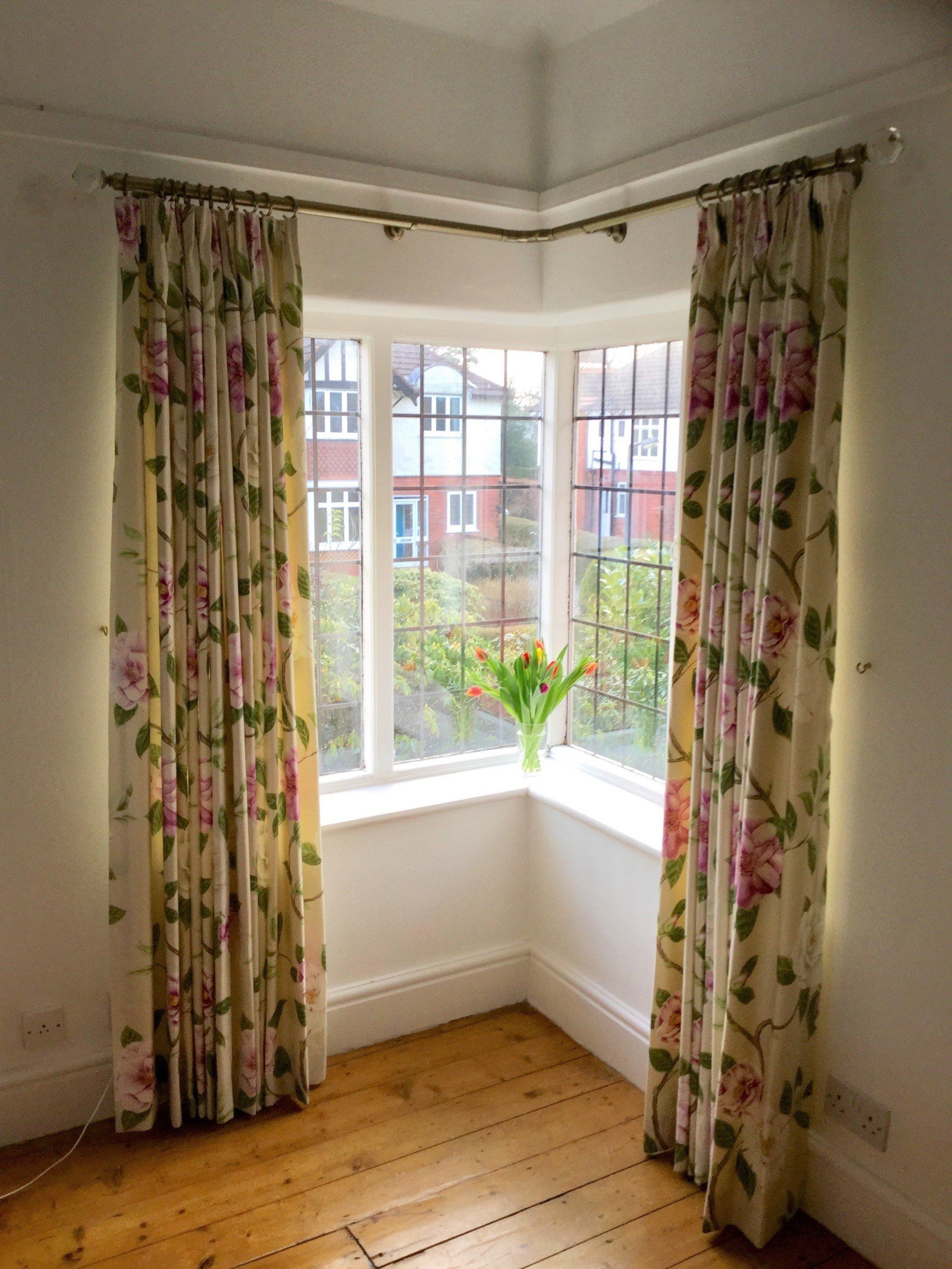 A room with a large window and floral curtains