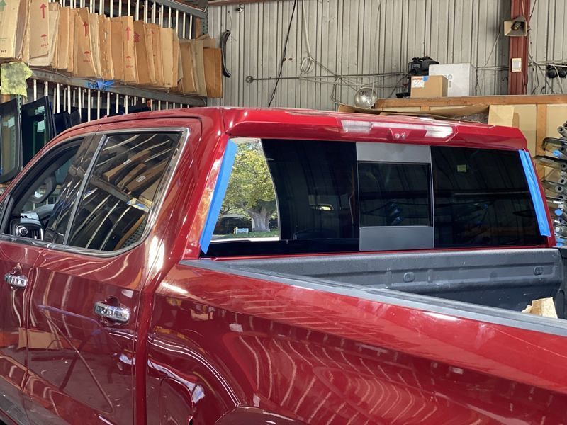 Red pickup truck with rear window replacement in a workshop