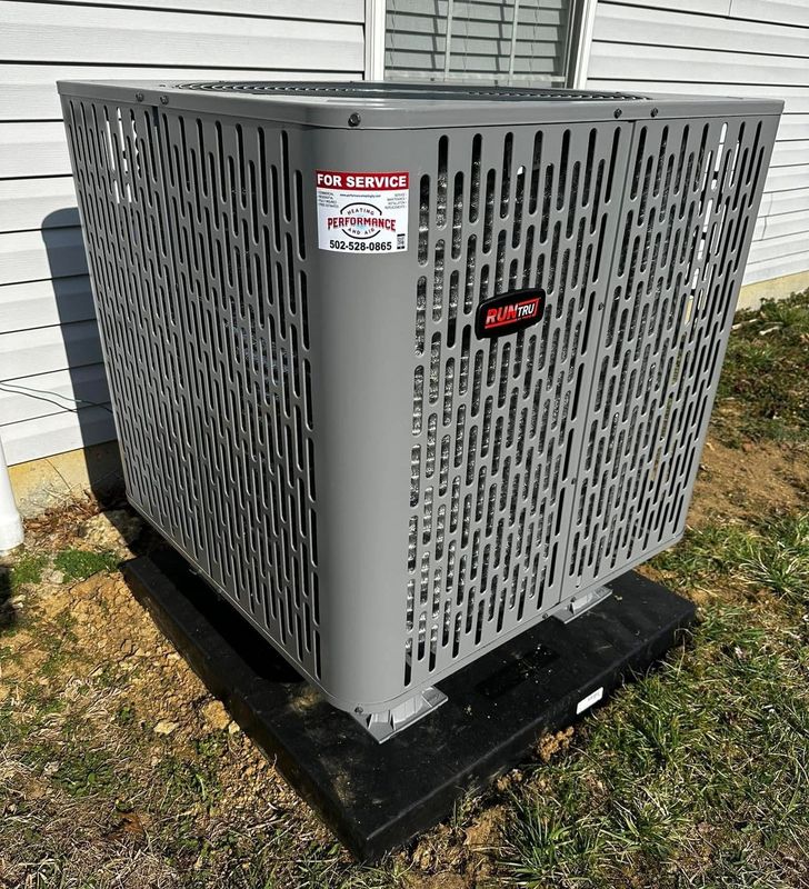 A large air conditioner is sitting on the ground in front of a house.