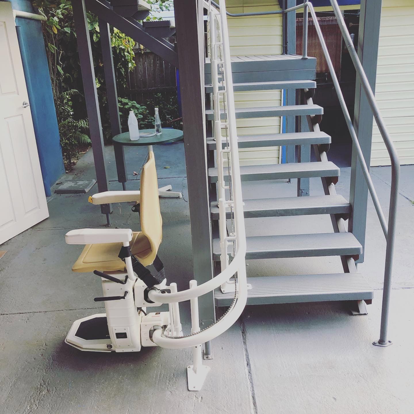 Exterior staircase with a wheelchair lift. Gray metal steps, white lift, tan seat.