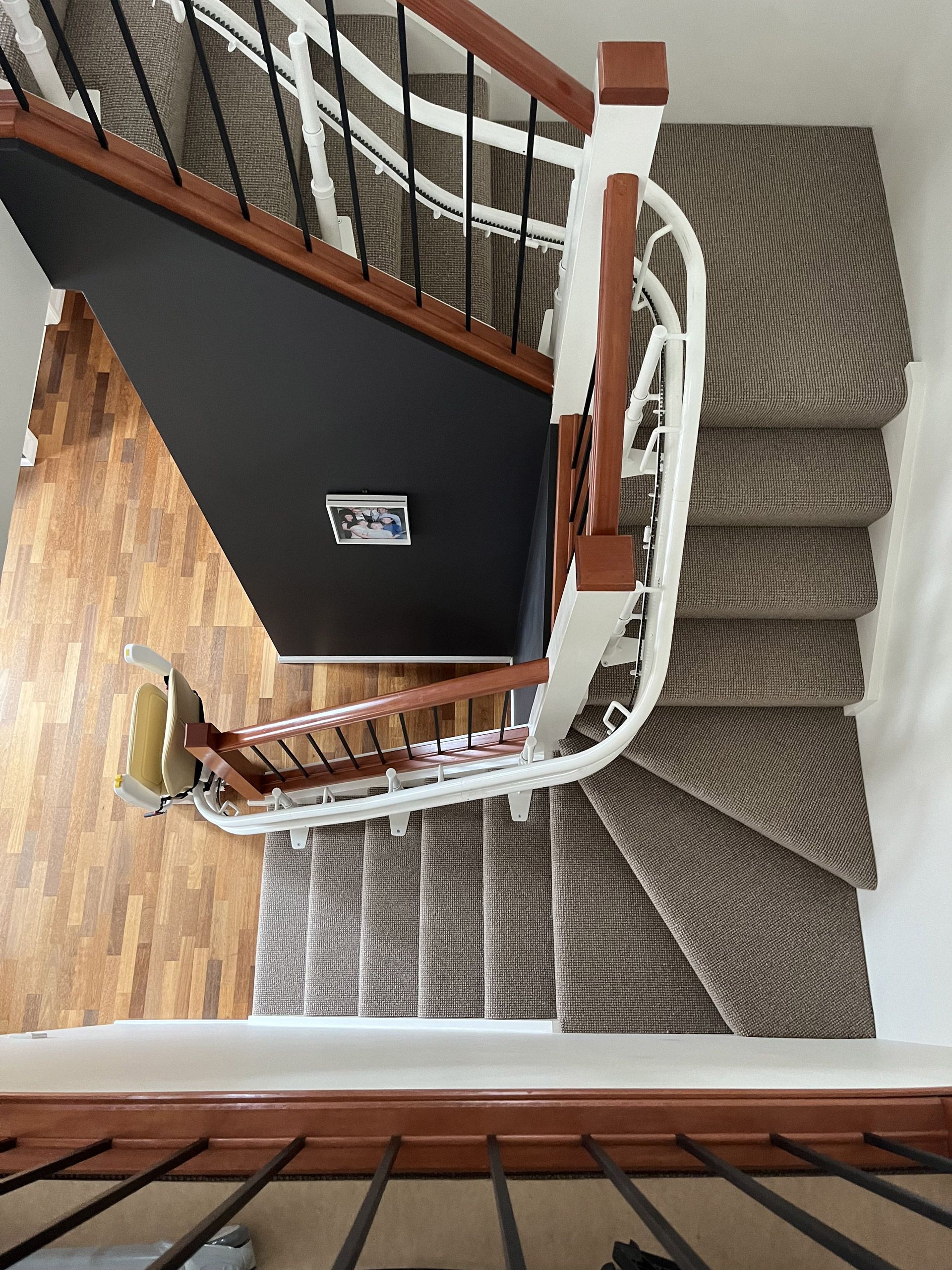 Staircase with brown carpet and wooden railing. Angled view from above.