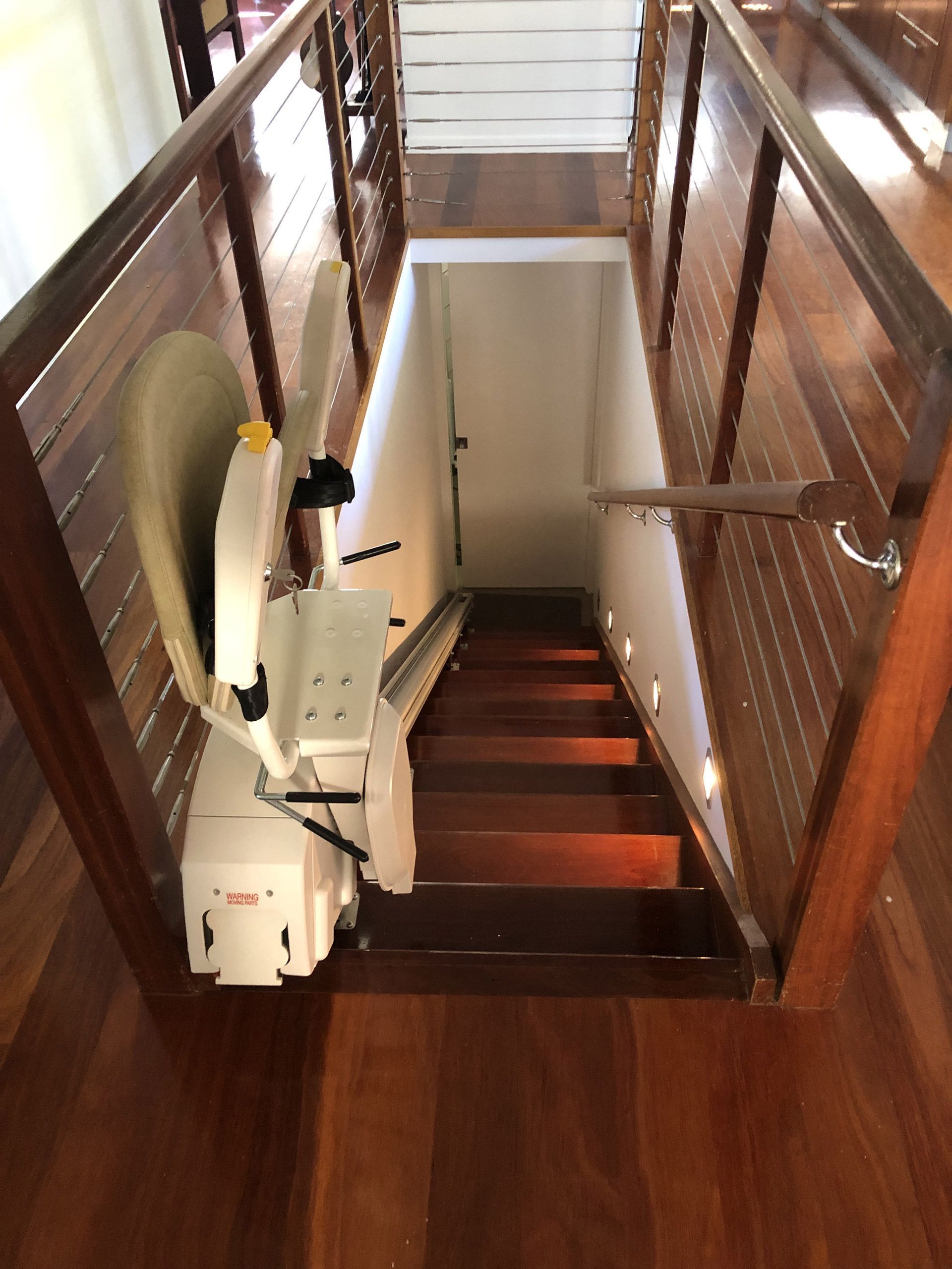 Stair lift installed on wooden staircase with matching wooden railings.