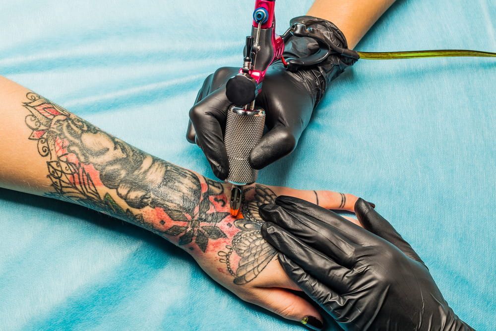 Tattoo Artist in Black Gloves Tattooing a Wrist — Whitsunday Tattooing Airlie Beach in Proserpine, QLD