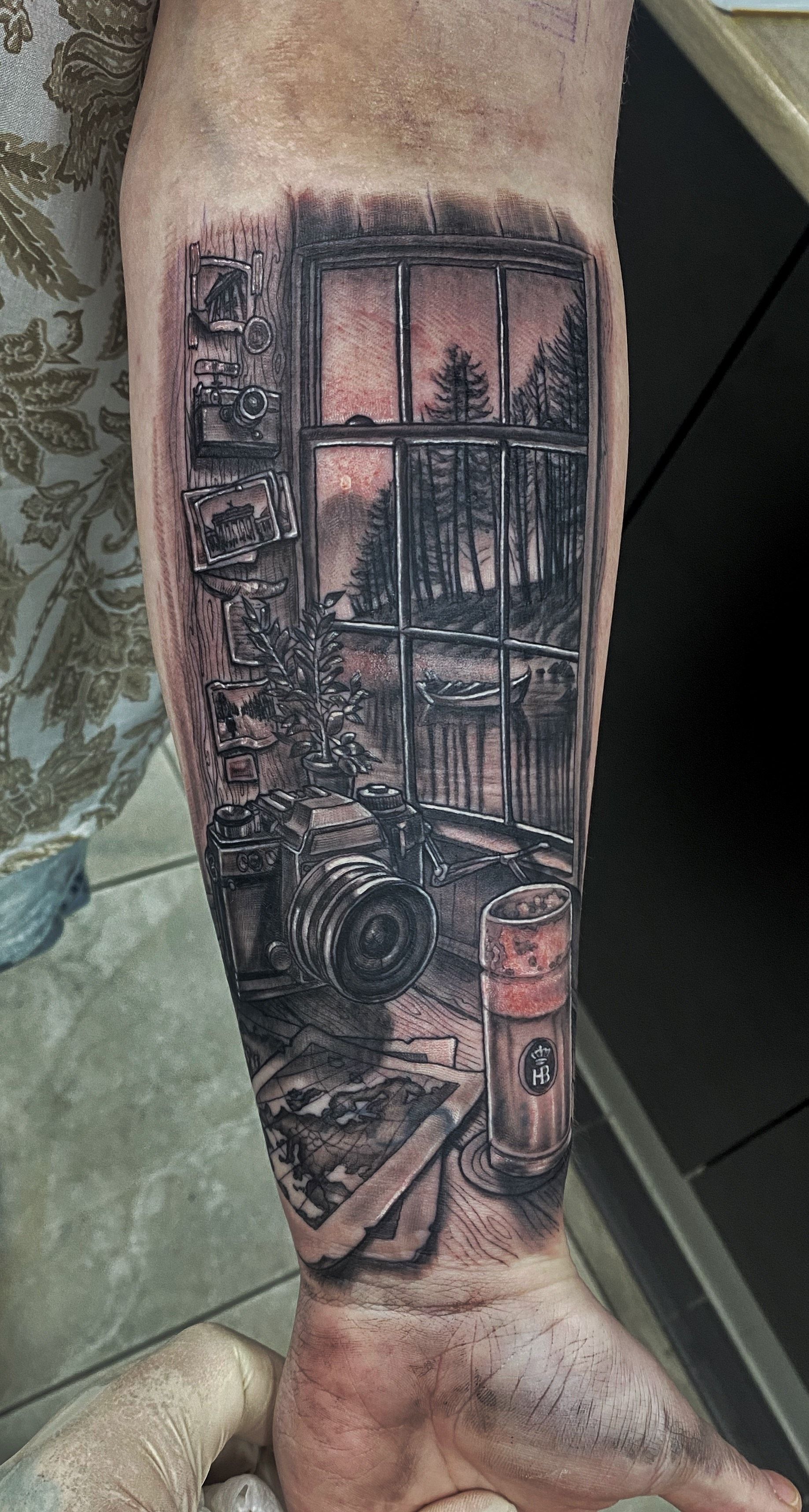 Tattoo of a window scene: an interior with a view of a forest and lake, detailed in black ink. — Whitsunday Tattooing Airlie Beach in Whitsundays, QLD