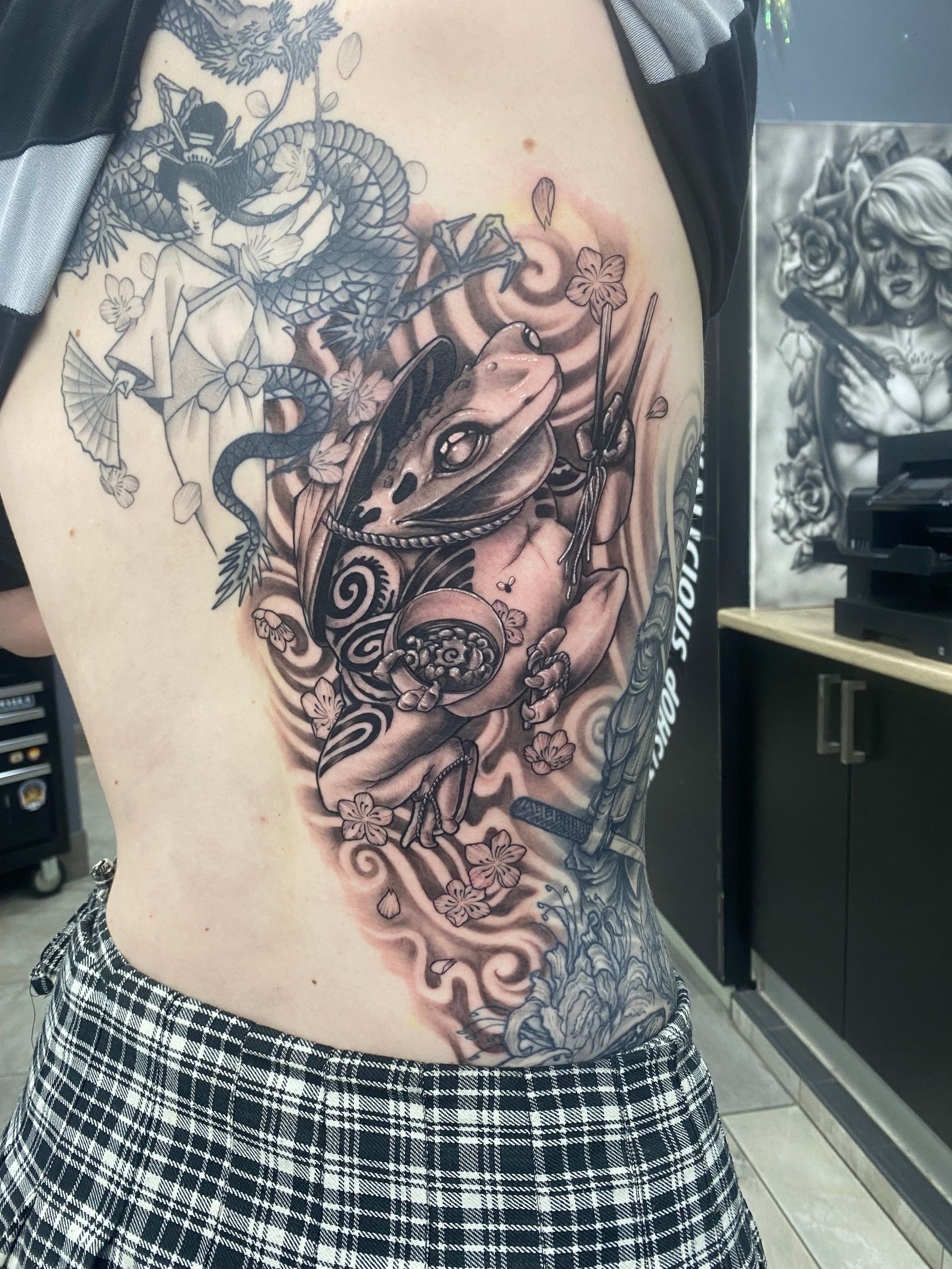 Tattoo on a person's side, featuring a dragon and floral elements in black and gray ink. — Whitsunday Tattooing Airlie Beach in Whitsundays, QLD