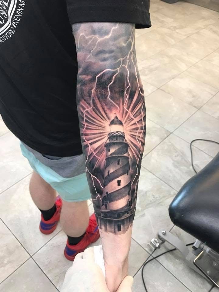 Tattoo of a lighthouse with lightning and light rays. Forearm with black and grey ink. — Whitsunday Tattooing Airlie Beach in Whitsundays, QLD
