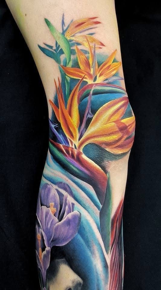Tattoo of vibrant Bird of Paradise flowers and a purple flower on an arm, with blue and green hues. — Whitsunday Tattooing Airlie Beach in Whitsundays, QLD