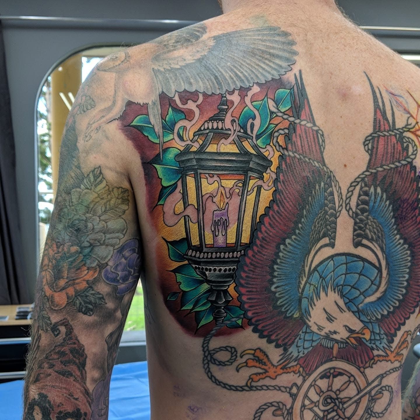 Back tattoo featuring a lantern and an eagle. Red, blue, yellow, and green colors. — Whitsunday Tattooing Airlie Beach in Whitsundays, QLD