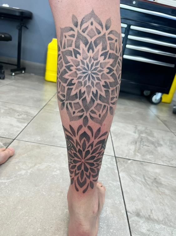 Leg tattoo with two gray mandala designs.