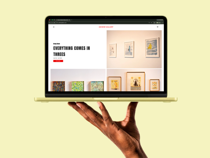 Laptop displaying an art gallery website, held up by a hand against a pale yellow background