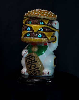 Art by Rich M Stevens. White lucky cat figurine with a burger-like stack on its head against a dark background