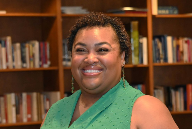 Kim Rockas in a green top standing in front of bookshelves in a library