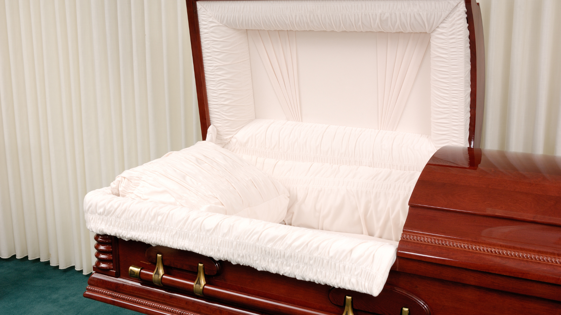 A wooden coffin with the lid open is sitting in a room.